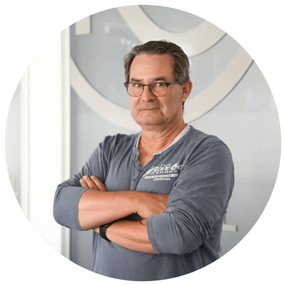 Michael Bauer, Senior Software Developer bei Kalkül IT, mit verschränkten Armen und Brille vor Firmenlogo im Büro.